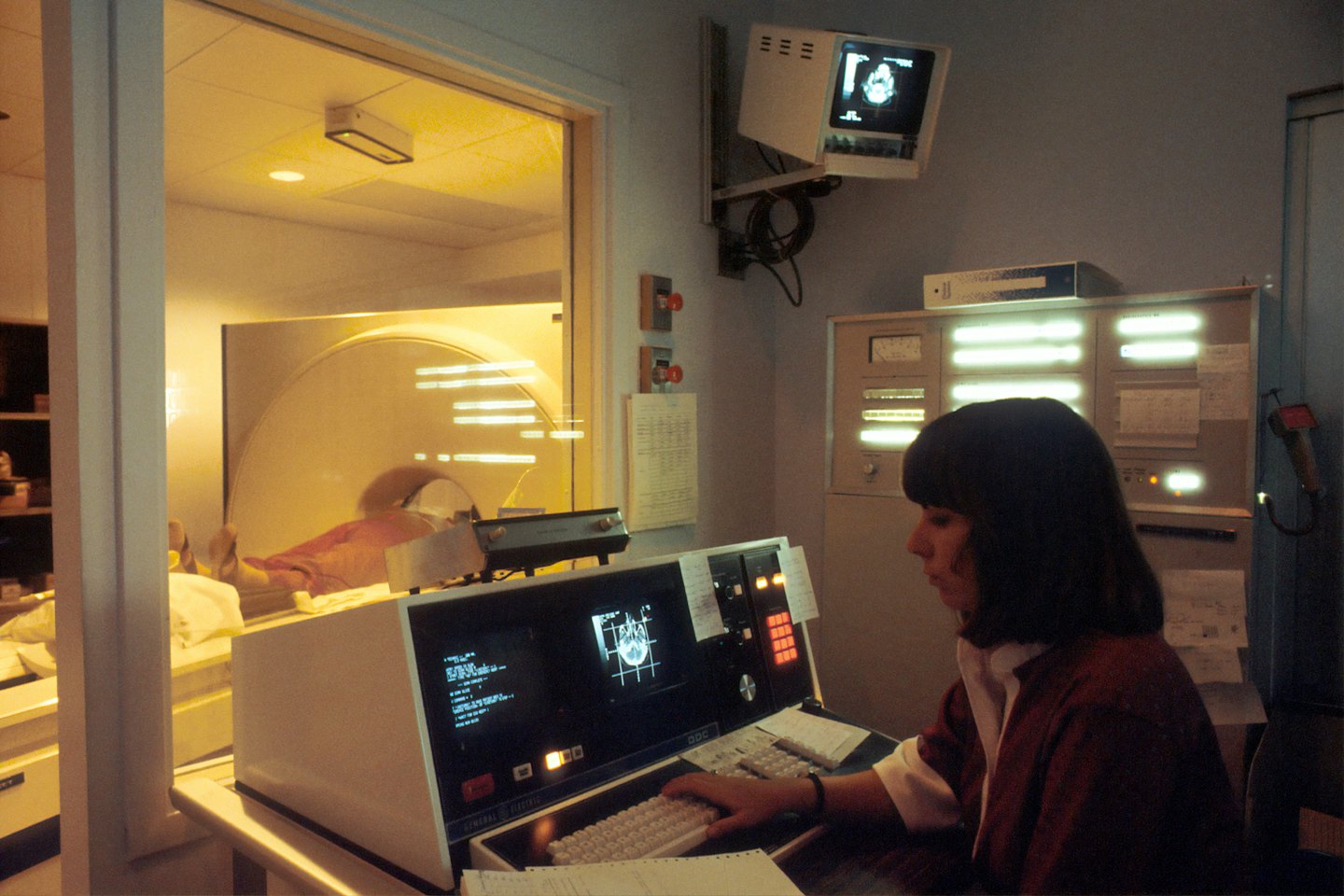 Tecnico monitora scansione paziente su console apparecchiatura di imaging.